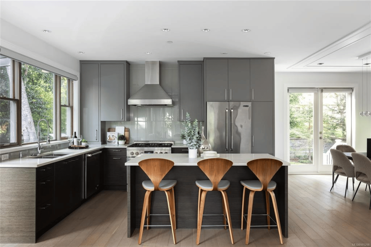 A stylish, modern kitchen featuring quartz countertops, energy-efficient stainless steel appliances, and a large island with wooden bar stools.