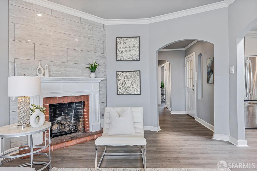Living room with a stone-tiled fireplace, white lounge chair, and arched hallway opening.