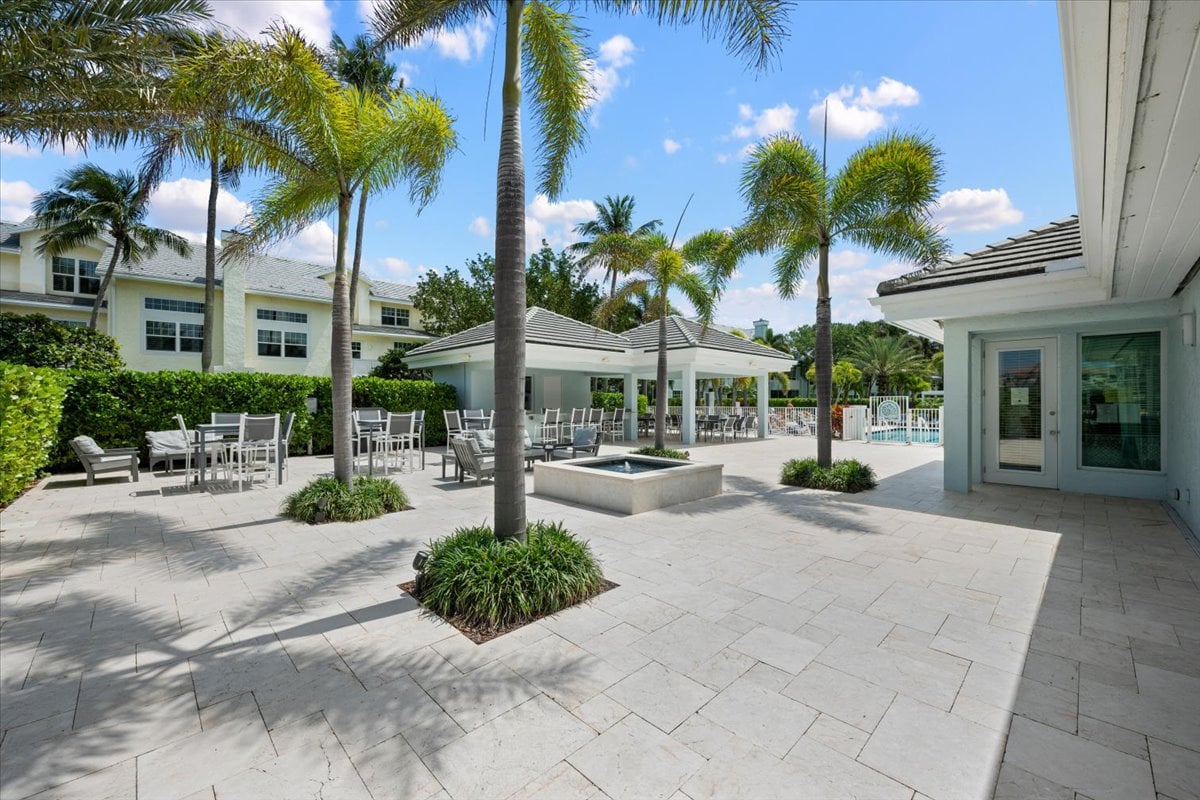 Condominium courtyard with palm trees, patio seating, a covered pavilion, and a pool.