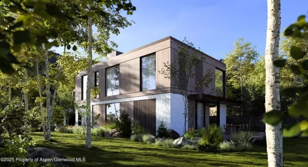 Modern two-story home with broad windows and wood siding, nestled among trees beside a landscaped lawn.