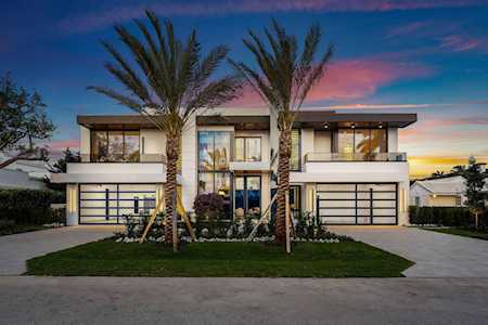 Modern two-story home with twin garage doors and tall palms, photographed at dusk.