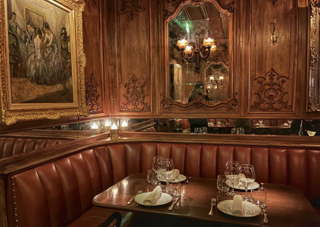 Restaurant booth with curved leather seating, carved wood paneling, and a set dining table.