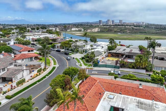 Aerial view of Newport Beach and Costa Mesa showcasing luxury waterfront homes, coastal neighborhoods, and the Southern California shoreline at sunset.