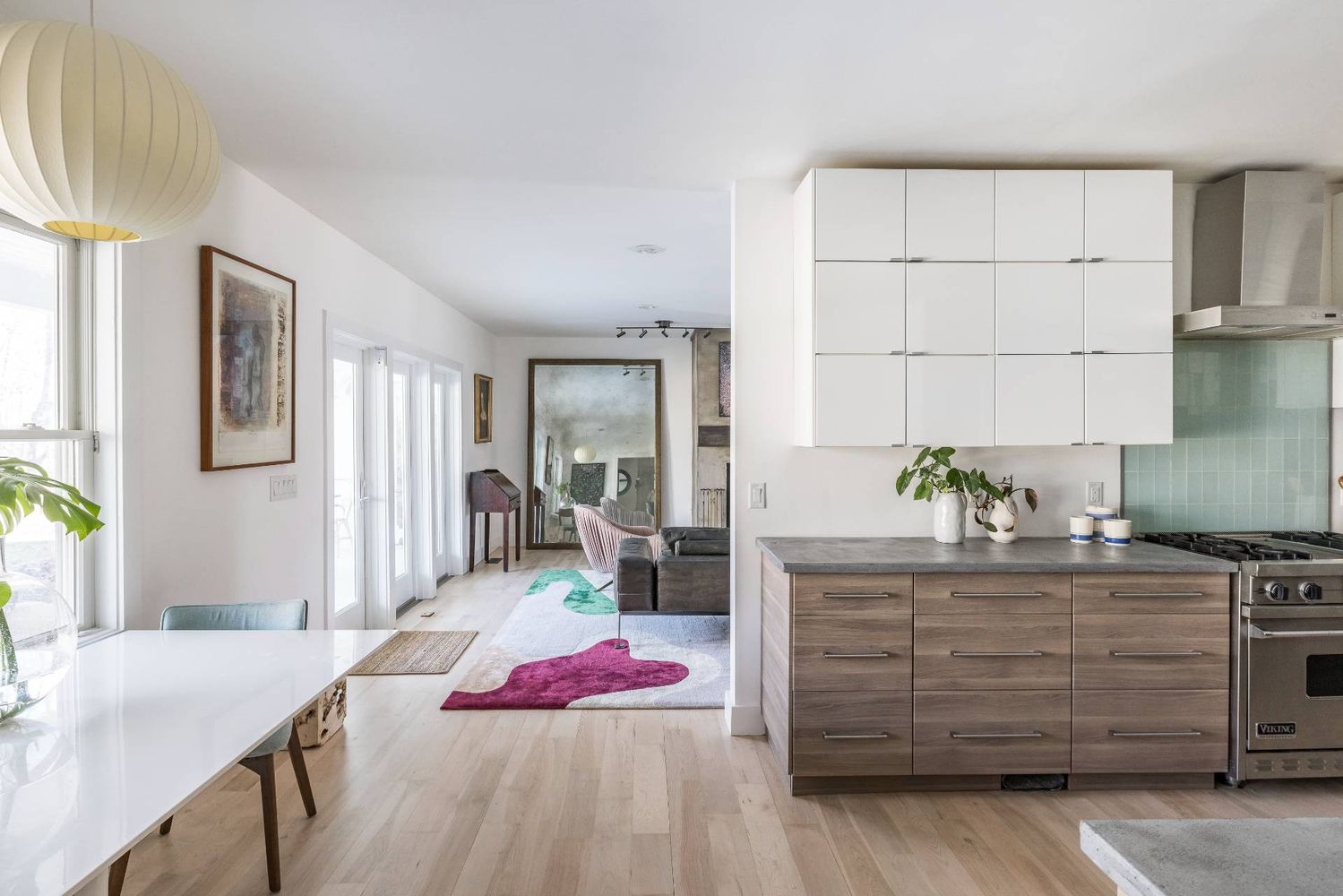 Open-plan kitchen with a wood-finish island and white cabinets, opening onto the dining and living areas.