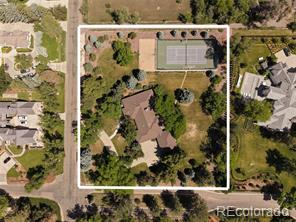 Aerial view of a wooded property with a tennis court and outlined parcel.