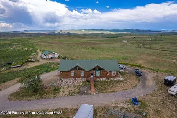 Brick house with a green roof and outbuilding amid open rural land near Craig.