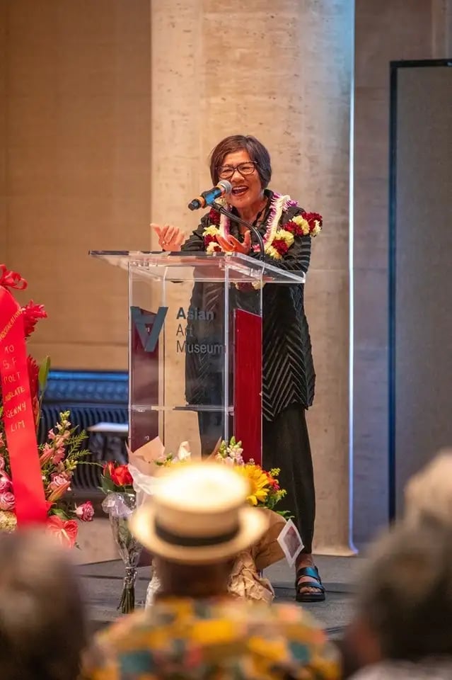 Genny Lim speaking at a podium with an engaged audience