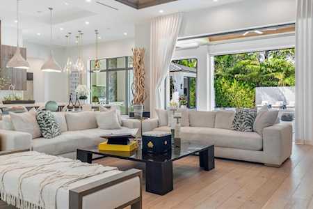 Open-plan living room with a cream sectional and glass doors overlooking greenery.