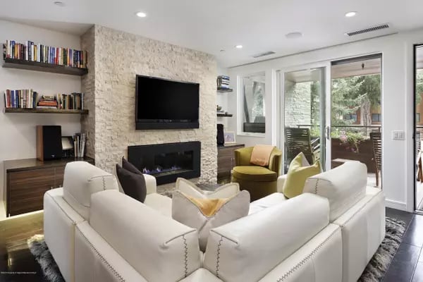 Living room with a white sectional, stone fireplace wall, and glass doors to a patio.