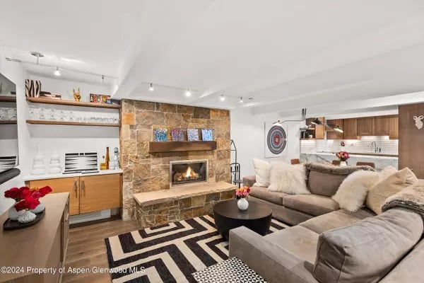 Living room with a stone fireplace, sectional sofa, and geometric rug.