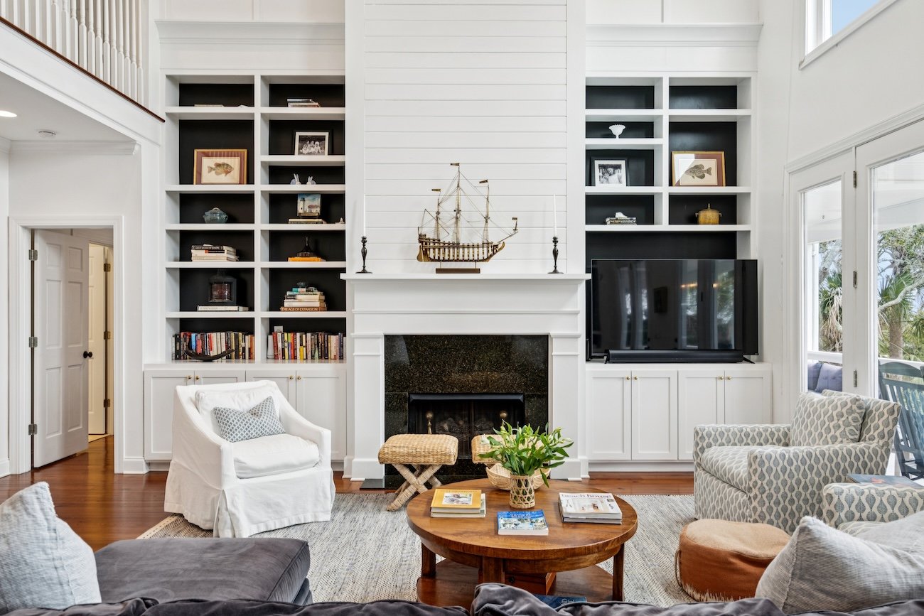 Living room with a tall white fireplace, built-in shelves, and seating around a wooden coffee table.