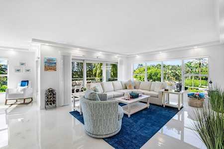 Bright living room with white seating, a deep blue rug, and broad windows overlooking a green garden.