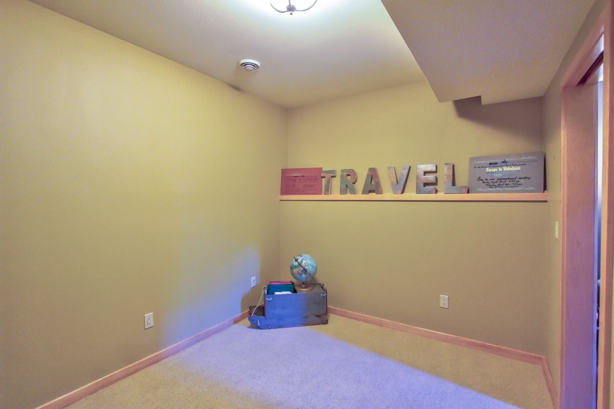 Carpeted room with beige walls, pink trim, a travel-themed shelf and a globe.