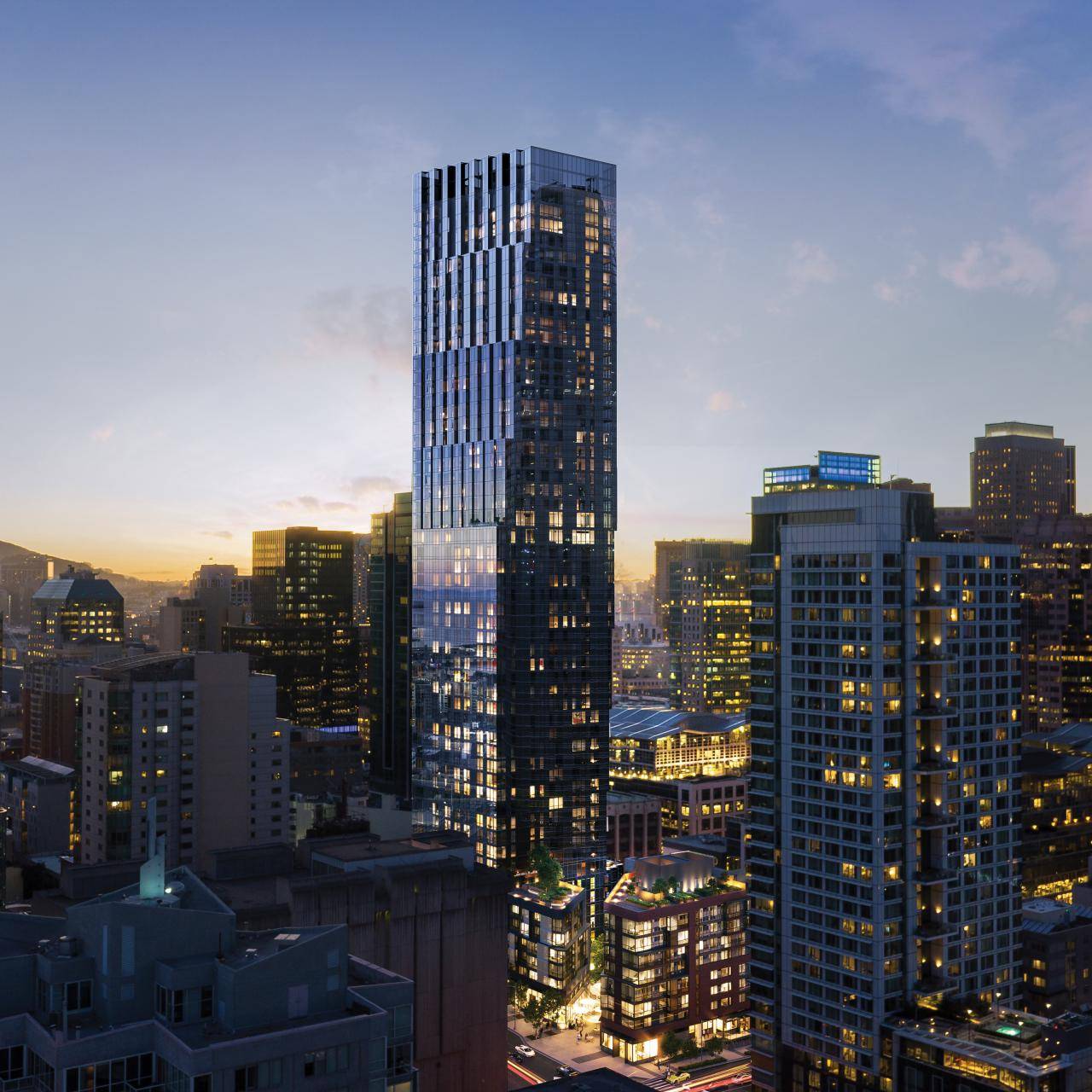 Glass high-rise tower among downtown buildings at dusk, with city lights beginning to glow.
