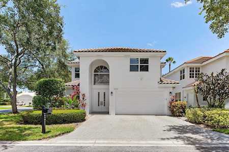 White stucco home with an arched entry, attached garage, and terracotta tile roof.