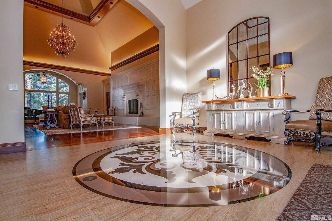 Luxury home foyer with a circular floor medallion, paneled console, and adjoining living room.