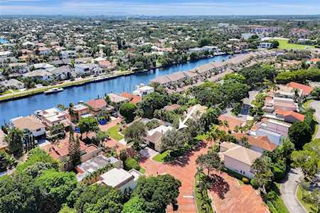 Aerial view of homes along a canal, with a white arrow pointing toward one property.