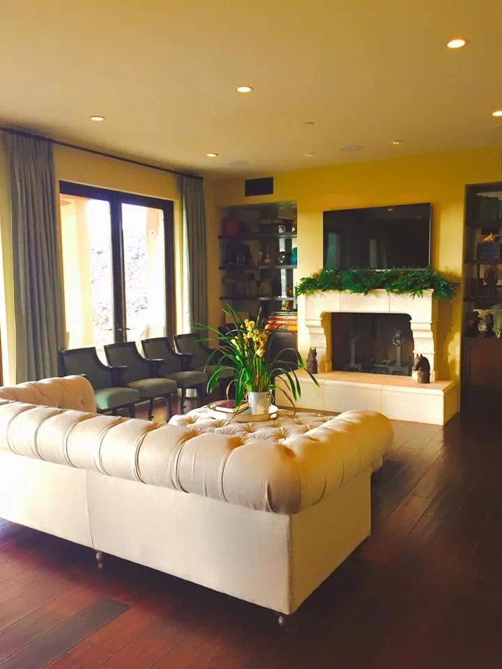 Living room with a cream tufted sectional facing a fireplace decorated with greenery.