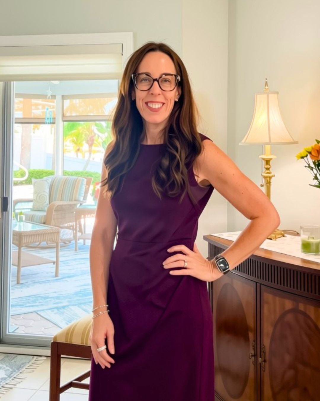 Karen Crotty in glasses and a purple dress in a bright living room.