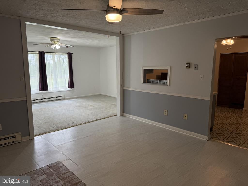Open interior with a tiled room leading to a carpeted living room with a large window.