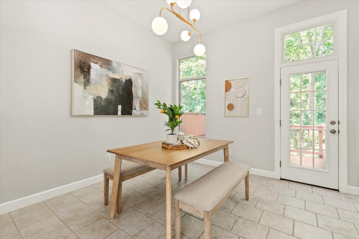 Dining area with a wooden table and bench beside a glass door leading to a deck.