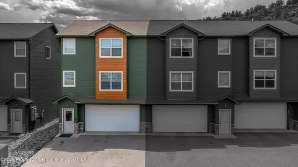 Attached townhomes with garage doors; one green-and-orange section stands out against the grayscale exterior.