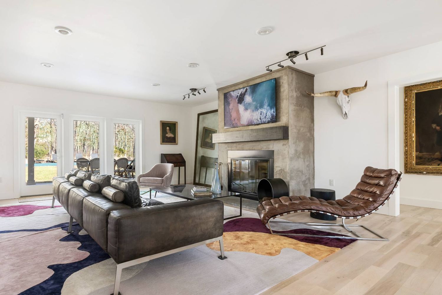 Living room with a concrete fireplace, leather sectional, and chaise lounge beside glass doors to the patio.