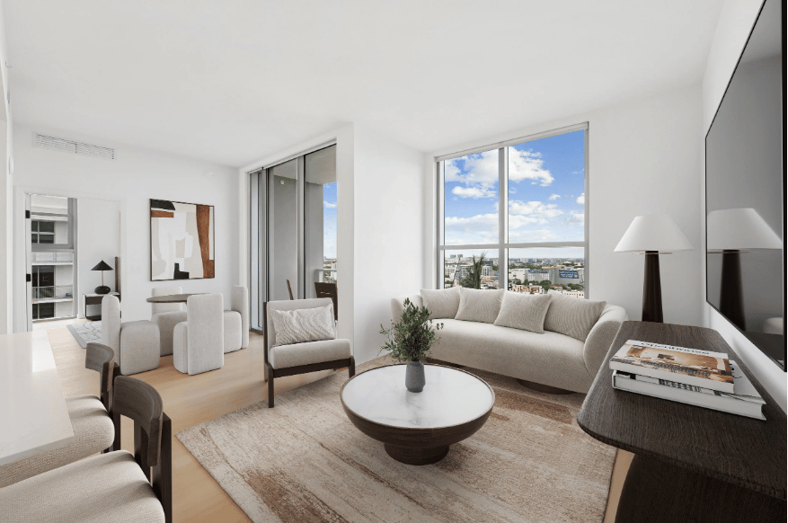 Furnished living room with a curved cream sofa and large windows overlooking the city.