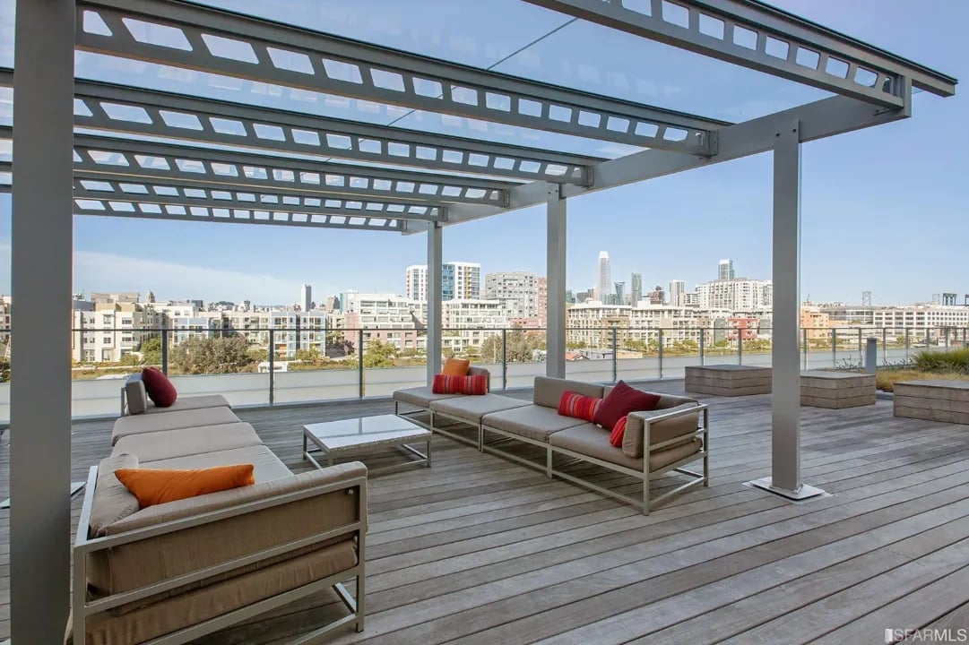 Arden Residences rooftop lounge with outdoor sofas and a metal pergola, with a city view.