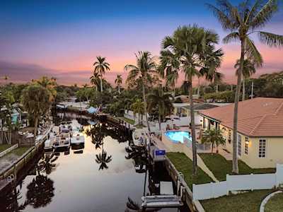 Aerial view of canal-side homes with private docks and palm trees at dusk.