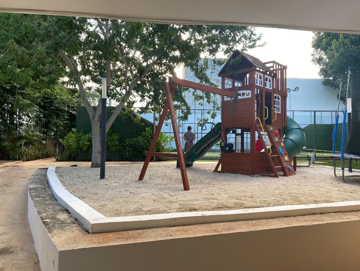Residential playground with a wooden climbing structure, slides, swings and sand play area.