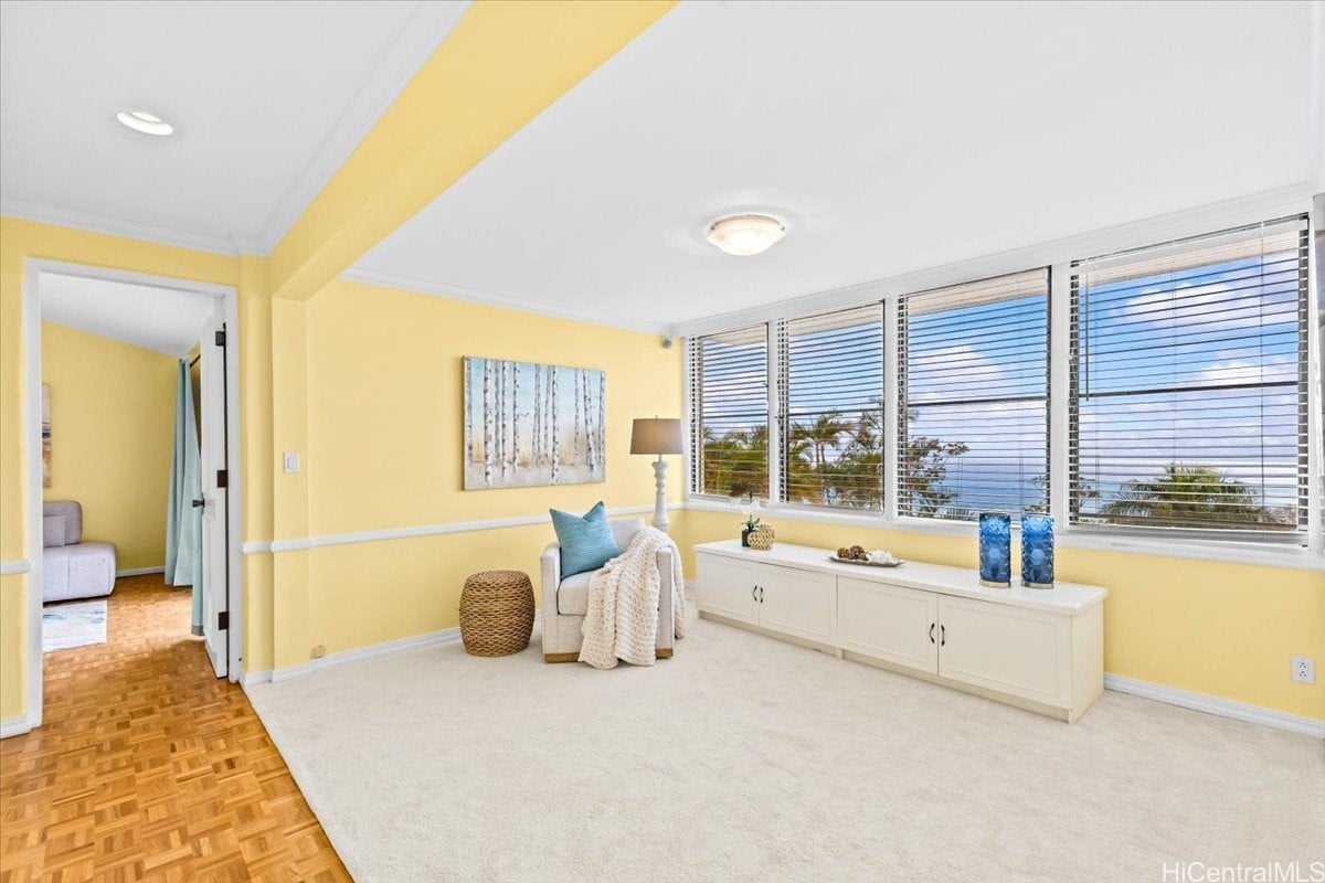 Bright sitting room with yellow walls, ocean-view windows, a white built-in cabinet, and parquet flooring.
