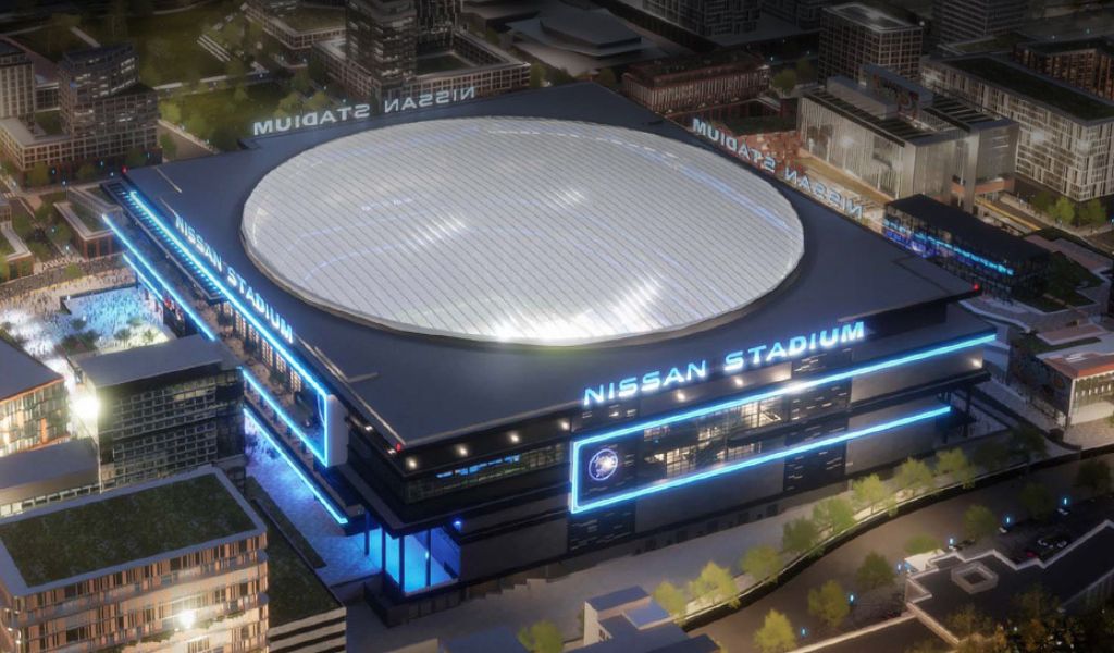Nissan Stadium at night, viewed from above with its oval roof and blue lighting.