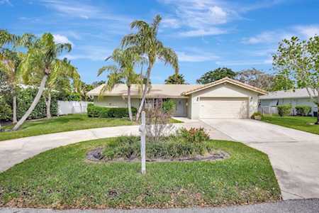 Single-story home with an attached garage, curved driveway, and palm trees in the front yard.