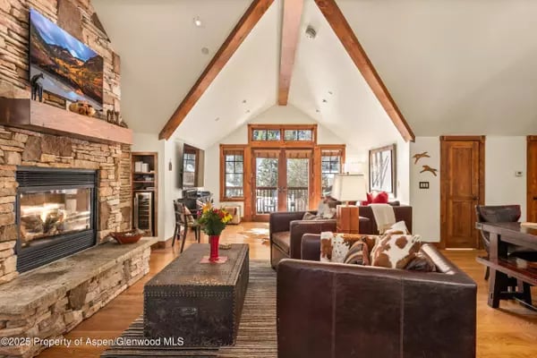 Living room with a stone fireplace, vaulted timber ceiling, and leather sofas.