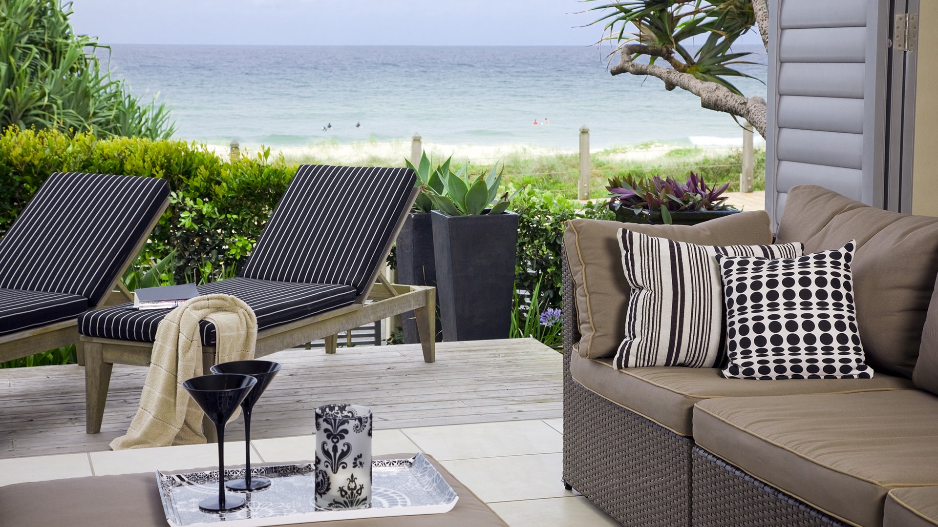 Seaside patio with lounge chairs and cushioned seating overlooking the ocean.