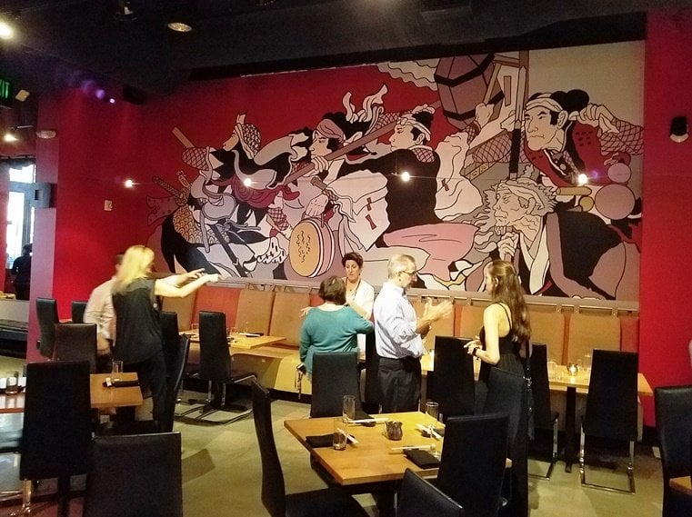 A vibrant restaurant interior featuring a large mural and diners engaged in conversation.