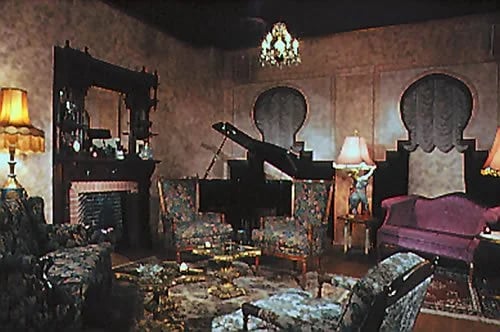 Ornate Club Lua lounge with a purple sofa, fireplace, patterned rugs, and chandeliers.