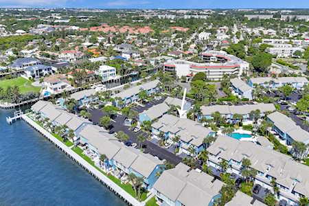 Aerial view of waterfront homes along a broad waterway, with docks and swimming pools.
