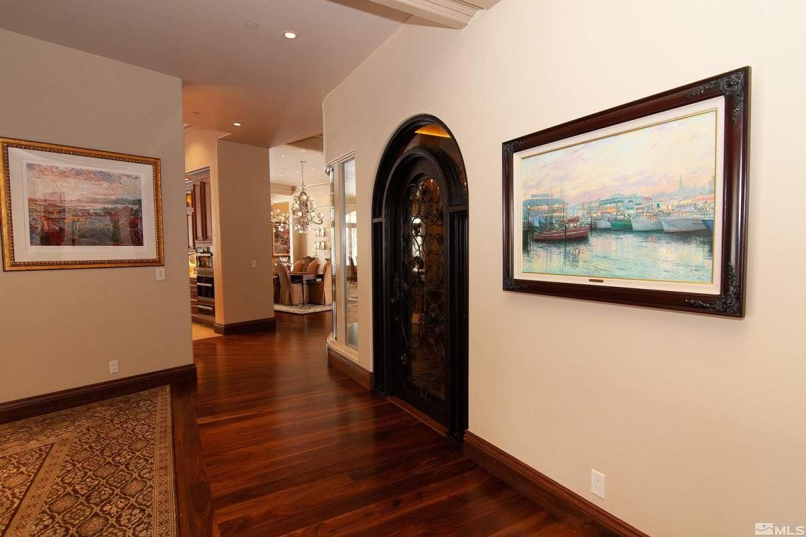 Foyer with polished hardwood floors, an ornate arched door, and framed artwork.