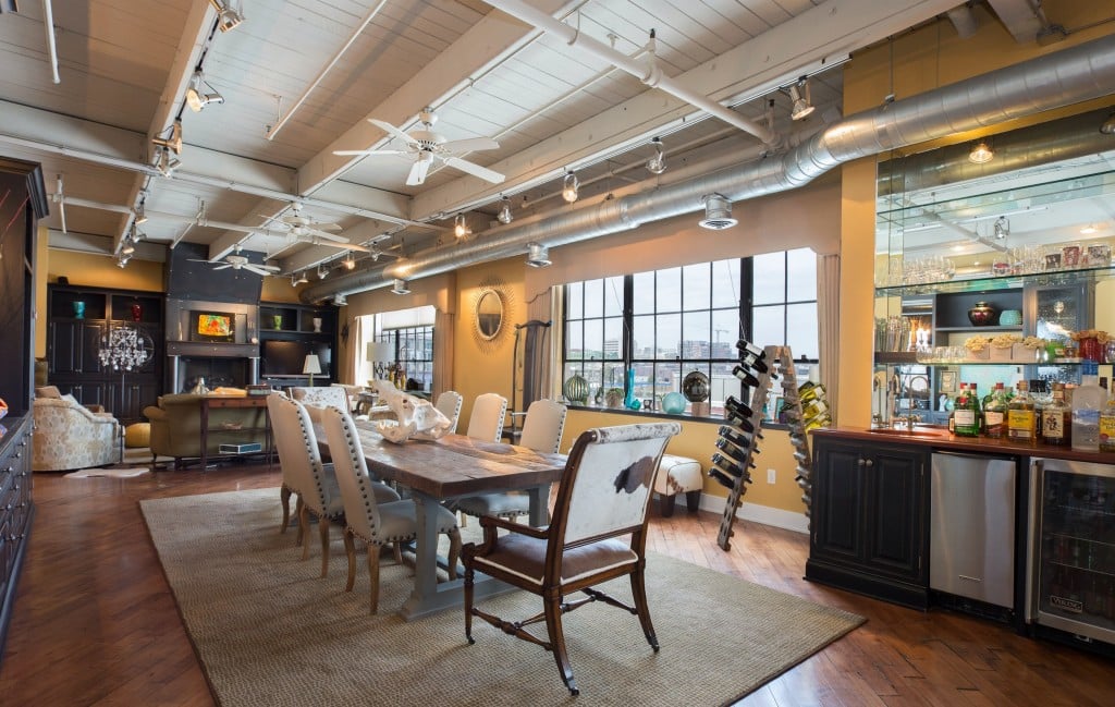 Furnished dining area with a long table, upholstered chairs, exposed ceiling beams, and built-in bar cabinetry.