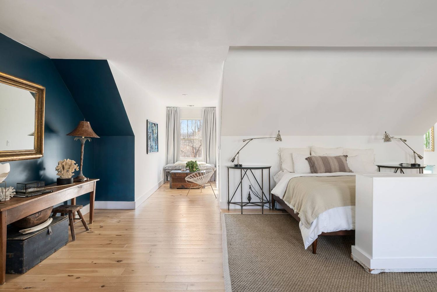 Bedroom with a king-size bed beneath a sloped ceiling and a deep teal accent wall.