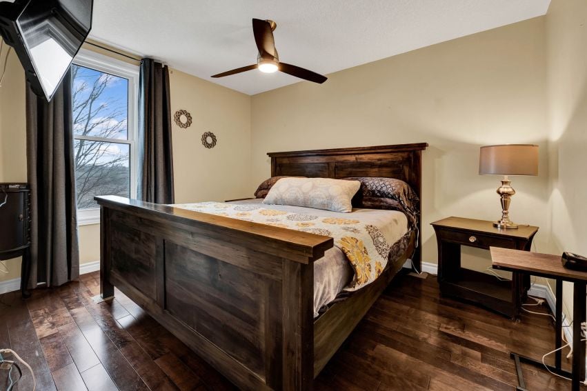 Bedroom with a dark wood four-poster bed, patterned bedding, and a large curtained window.