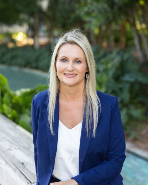 Charmaine Ebben in a navy blazer beside a swimming pool.