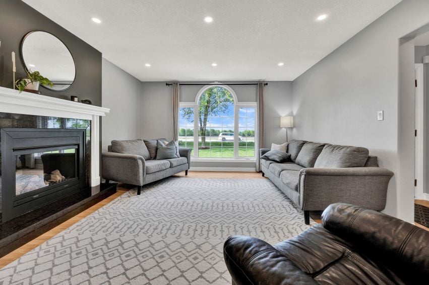Living room with gray sofas, a dark fireplace, and a large arched window.