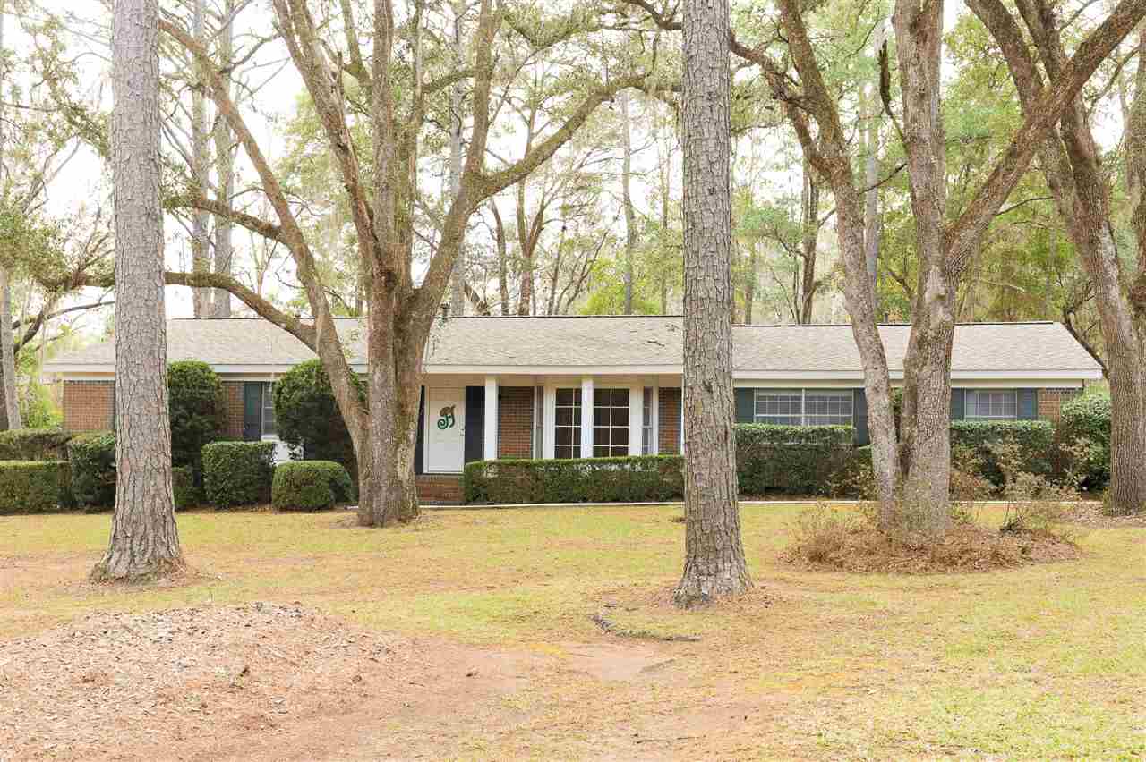 A brick home surrounded by trees and a lush green lawn, showcasing a serene and inviting outdoor environment.