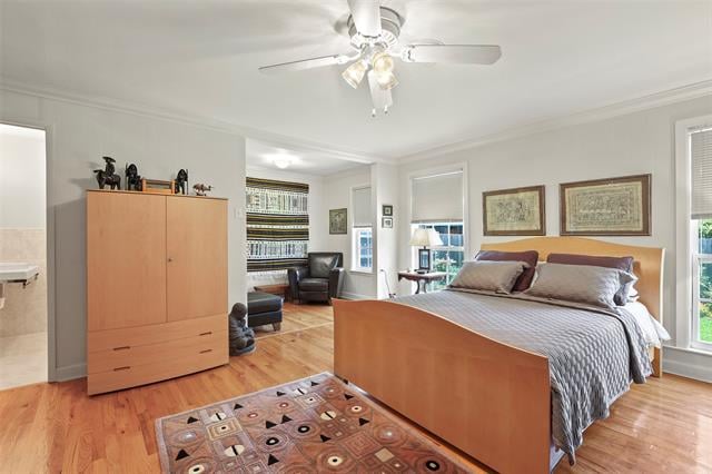 Bedroom with a wooden bed, framed prints, hardwood floors, and a sitting area with built-in shelves.