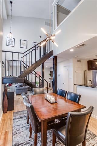 Dining area with a long wooden table and leather chairs beneath a staircase and loft.