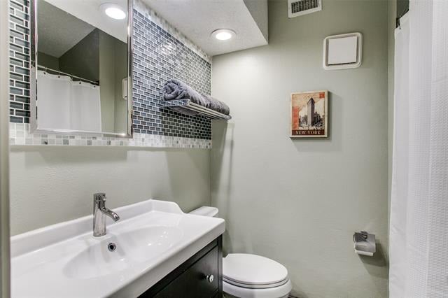 Bathroom with a white sink, dark vanity, mirrored wall, and gray mosaic tile shelf.