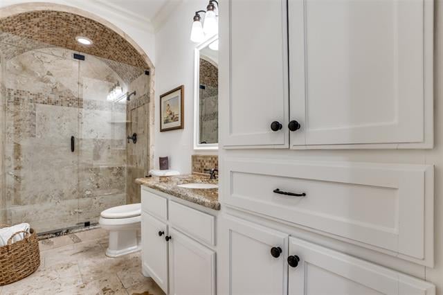 Bathroom with an arched glass-enclosed marble shower, white vanity, and granite countertop.
